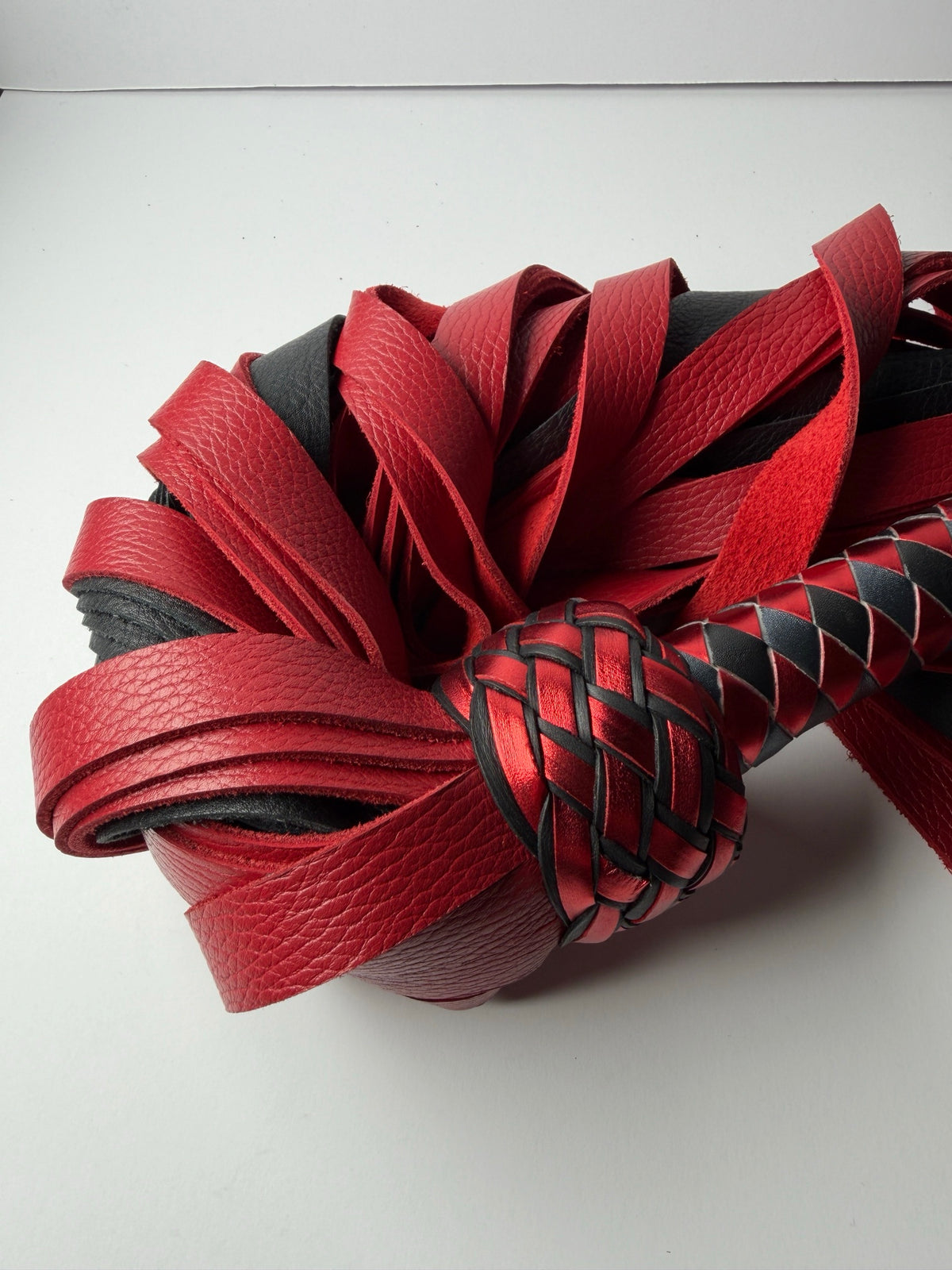 Close up of Garnet's metallic red Turk's head knot against the coiled red floater cowhide falls