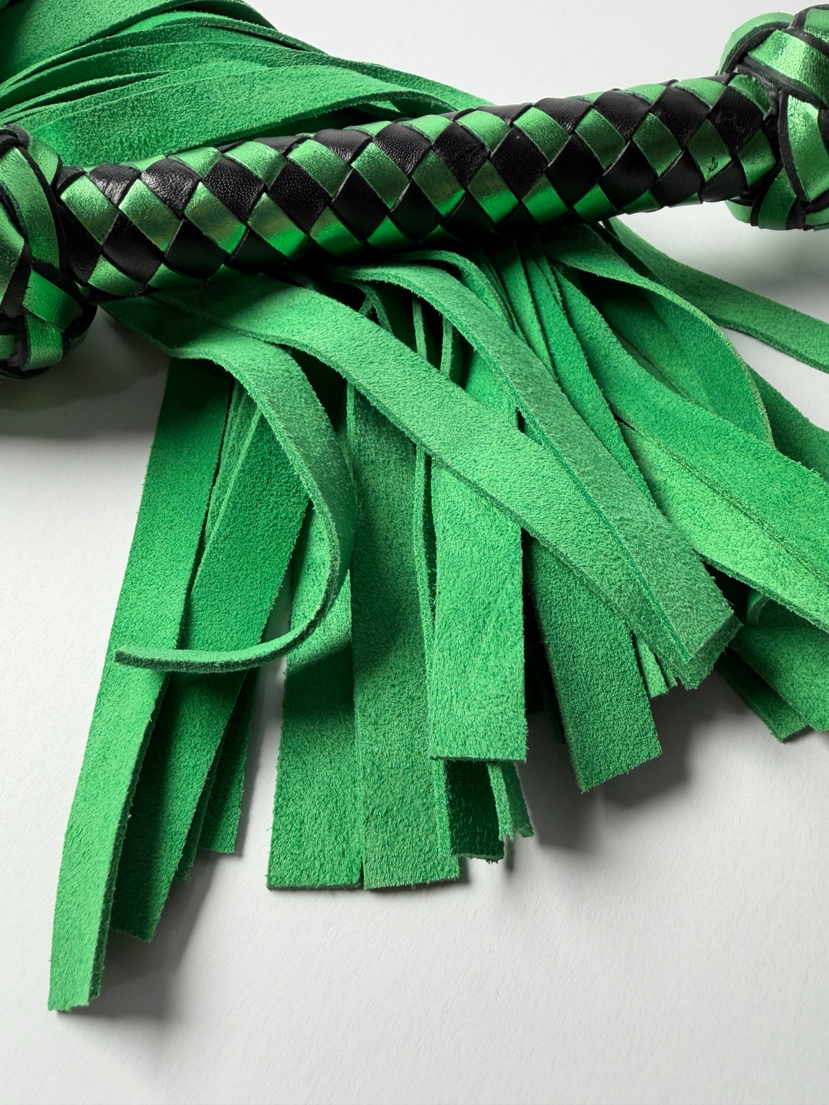 Peridot's green cowhide suede fall tips beneath the metallic green and black braided handle