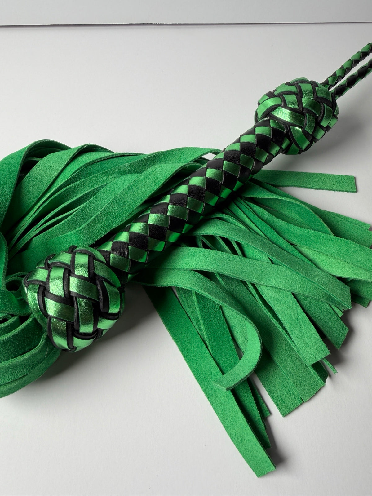 Peridot metallic green and black braided handle between two Turk's head knots over green suede falls