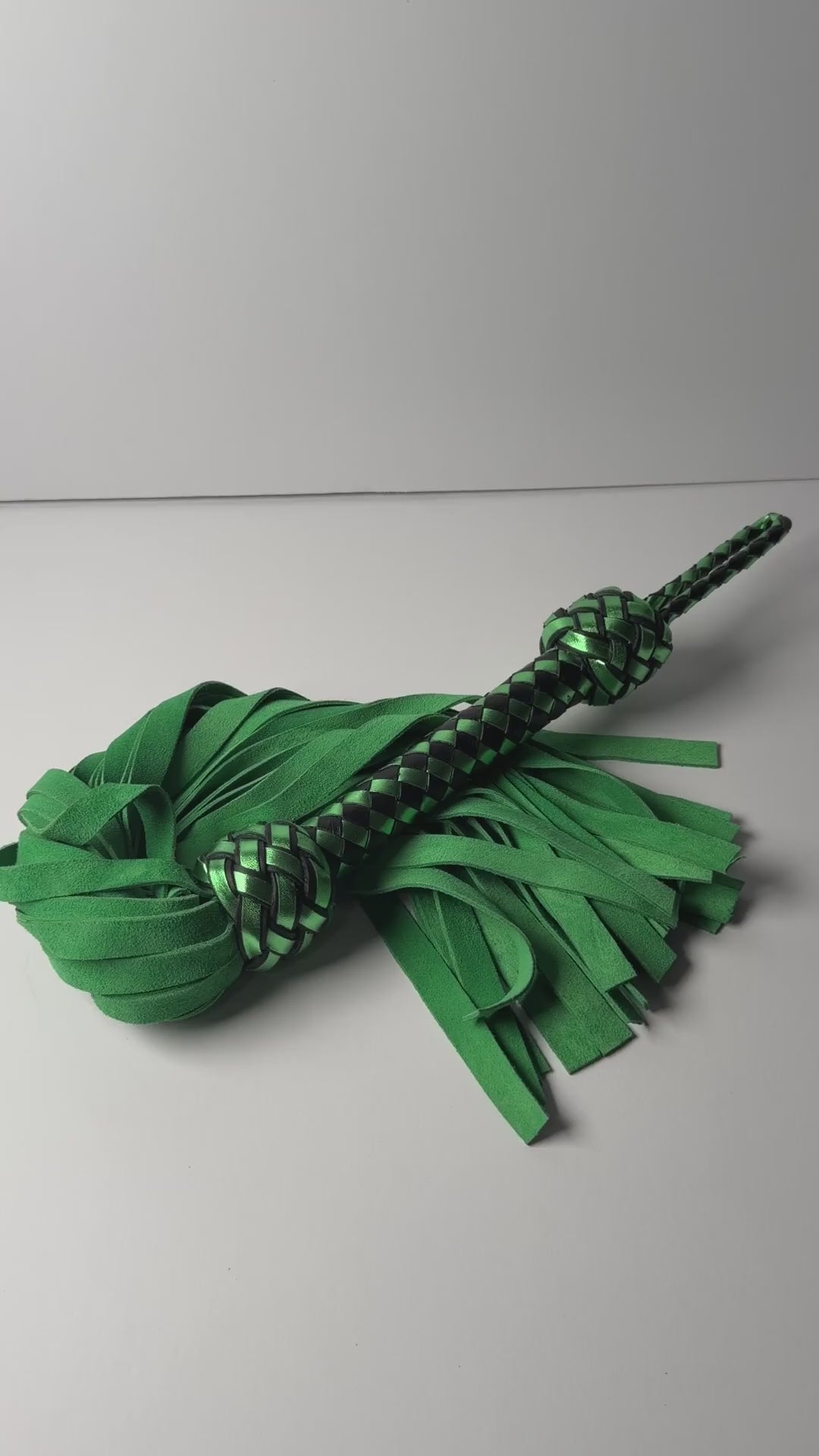 Video of the Peridot flogger, green cowhide suede with a metallic green and black braided handle