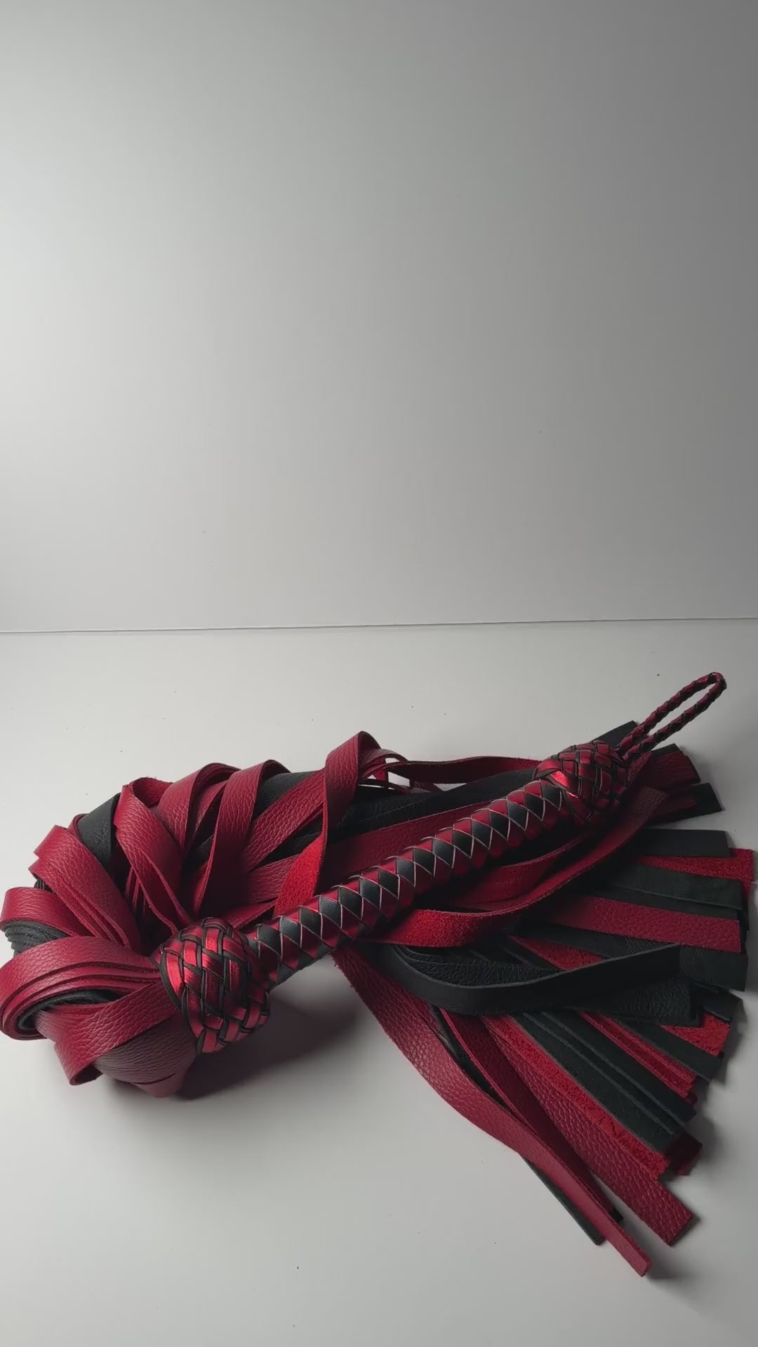 Video of the Garnet flogger, red and black floater cowhide with a metallic red and black braided handle