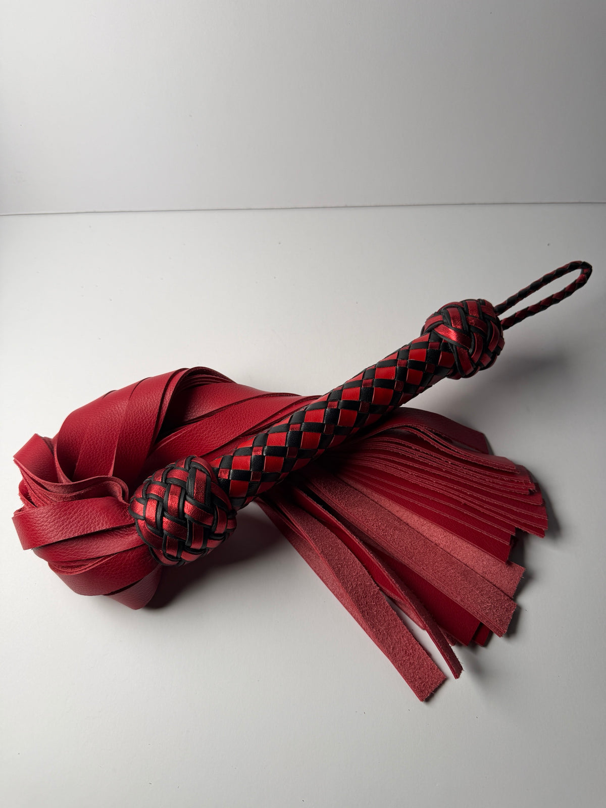 Vermilion flogger, red cowhide falls with a red, metallic red and black diamond braid handle and loop